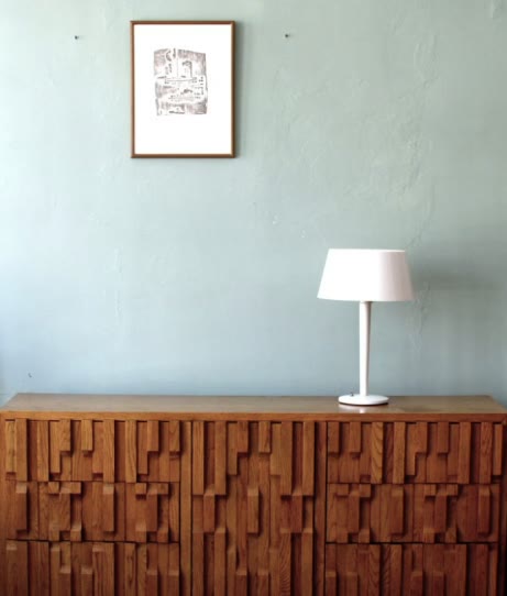 Formiture — A slatted wood sideboard and lamp on a mint wall