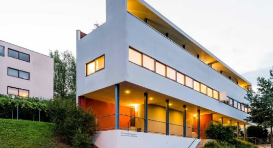 Formiture — A white modernist house lit from inside at dusk