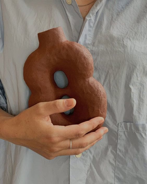 The Clay — A terracotta sculptural form held against linen